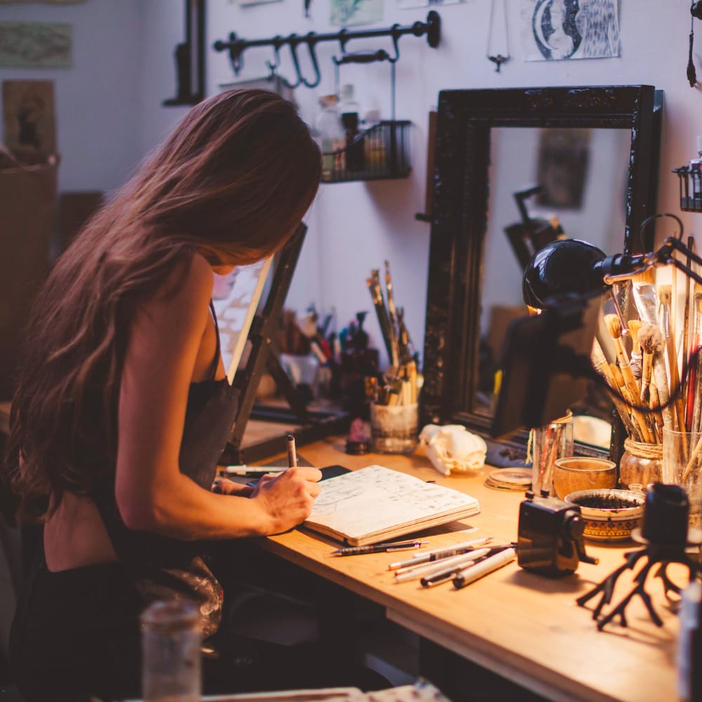 Artist drawing in workbook at workstation